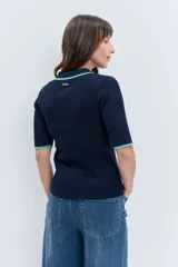 Jersey de punto acanalado en color azul marino, con cuello tipo polo y detalles en color verde menta en el borde del cuello y las mangas. Presenta cierre frontal con botones y mangas cortas.
