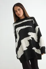 Buzo de punto con diseño estampado abstracto en blanco y negro, de corte holgado, cuello redondo y mangas largas con puños acanalados.