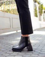 Botinetas de cuero negro con plataforma y taco cuadrado. Presentan un diseño combinado con una textura tipo reptil en la parte posterior y cierre lateral.