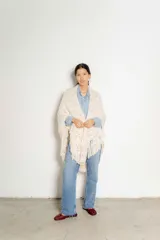 Chal triangular tejido a crochet en hilo crudo con detalles multicolores y flecos.