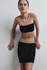 Falda mini de tiro bajo, confeccionada en tejido liso de color negro, con diseño minimalista y cintura elástica.