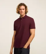 Remera polo de manga corta color verde militar, confeccionada en algodón peruano con cuello convencional y cierre de botones.