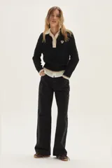 Sweater de punto con diseño de ochos en color crudo, con cuello polo y tapeta de botones en contraste verde. Presenta bordado en el pecho, puños y ruedo acanalados con detalles de rayas en verde.