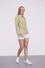 Blusa de algodón con estampado de hojas en tonos verdes sobre fondo blanco, cuello camisero, cierre frontal con botones y mangas largas.