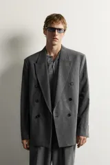 Blazer gris de corte relaxed fit con diseño de raya diplomática, cuello con solapas de pico, doble botonadura cruzada y bolsillos con solapa en la cadera.