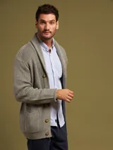 Cardigan azul de punto con cuello esmoquin, cierre con botones de madera y bolsillos frontales.