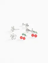 Set de caravanas plateadas con forma de flor y cerezas rojas con hojas verdes.