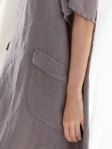 Vestido midi color visón, de lino, con cuello en V, mangas cortas y dos bolsillos frontales.