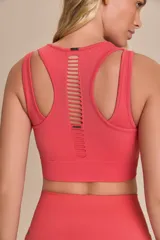 Top deportivo color coral, con cuello redondo y espalda deportiva. Presenta diseño acanalado y pequeñas aberturas decorativas.