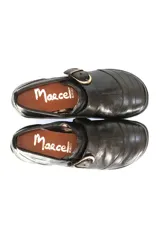 Zapato bajo de cuero negro con hebilla dorada.