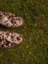 Botas de caña media con estampado animal print tipo vaca, taco ancho y punta redondeada. Cuenta con cierre lateral y diseño de pelo sintético.
