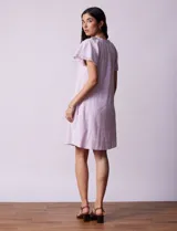 Vestido corto de lino a rayas verticales rosas y blancas, con cuello fruncido, escote en V con lazo de ajuste y mangas cortas con puntilla de crochet.