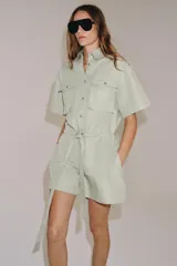Mono corto de Zara Woman Collection color verde menta, confeccionado en mezcla de algodón y lino. Presenta cuello solapa, manga corta, cierre frontal con botones, bolsillos de plastrón con solapa en el pecho y cintura ajustable con lazo.