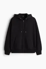 Campera canguro de felpa negra con capucha ajustable, cierre frontal completo y bolsillos tipo parche, de corte oversized.
