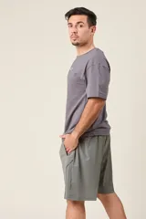 Bermuda deportiva color verde militar, de corte suelto, confeccionada en nylon. Cuenta con cintura elástica, cordón de ajuste, detalles de líneas en los costados y bolsillos con cierre.