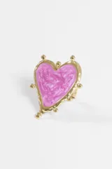 Anillo de acero dorado con diseño de corazón grande, esmalte rosado perlado en el centro y pequeños apliques esféricos en el borde.