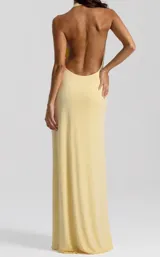 Vestido largo amarillo de diseño fluido, con escote halter pronunciado en V, drapeado en la cintura y una abertura lateral profunda en la pierna.