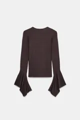 Camiseta de cuello redondo y manga larga, confeccionada en tejido rib con mezcla de lyocell. Presenta un diseño ajustado con terminación de volantes en los puños y bajo recto.