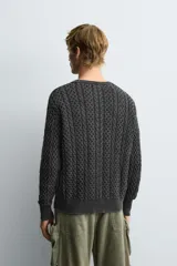 Jersey de corte relajado confeccionado en tejido de algodón con textura de trenzas. Presenta cuello redondo, manga larga y acabados en rib. Posee un efecto lavado que le otorga un aspecto único.