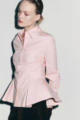 Camisa de popelín de algodón con cuello solapa, manga larga con puños y bajo con diseño peplum. Presenta cierre frontal con botones ocultos por solapa.