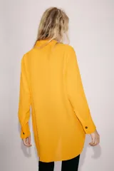 Camisa de viscosa color naranja de la colección ZW Collection de Zara, con cuello solapa, manga larga con puño, bajo asimétrico y cierre frontal con botones a contraste.