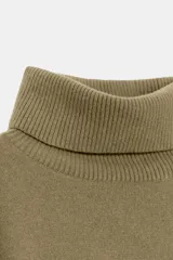 Jersey de corte oversize confeccionado en mezcla de lana, con cuello alto y manga larga. Presenta un diseño holgado con terminaciones en rib en el cuello, puños y ruedo.