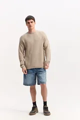 Sweater de cuello redondo y manga larga, confeccionado en tejido texturizado color beige claro, con diseño liviano y caída natural.
