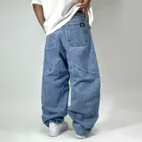 Pantalón de jean estilo ultra baggy con diseño de paneles curvos en las piernas. Presenta un lavado claro, bolsillos traseros amplios y costuras reforzadas que definen su silueta holgada y voluminosa.