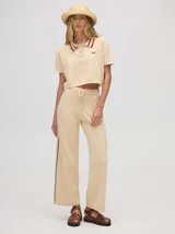 Pantalón de punto color beige con rayas laterales oscuras, tiro alto, pretina elástica con cordón de ajuste y corte holgado de pierna ancha.