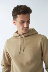 Buzo canguro color arena de felpa, con capucha ajustable, bolsillo tipo canguro, mangas largas y logo estampado en el pecho.