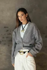 Cardigan de tejido suave en color gris, con escote en V, cierre frontal con botones y puños con detalle de botón.