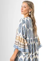Maxi vestido largo de fibrana en color blanco con estampado paisley y geométrico en tonos azules y tostados, con escote en V, mangas largas amplias y diseño holgado con volados en la falda.