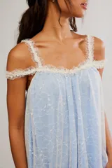Vestido corto de tul bordado color rojo y rosado, con escote recto, volados sobre los hombros, tiras finas regulables y ruedo terminado en volado. Caída suelta y liviana.