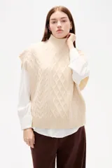 Chaleco de punto con diseño de ochos, cuello alto y corte holgado.