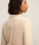Campera deportiva de microfibra color beige con cuello alto y cierre frontal de cremallera.