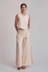 Pantalón marrón de corte palazzo, tiro alto, con pliegues frontales y pespuntes blancos decorativos.