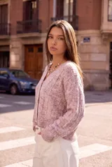 Cardigan de punto color rosa viejo con efecto jaspeado, escote en V y cierre frontal con botones. Mangas largas y puños acanalados.