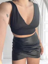 Minifalda negra de cuero sintético con frunces y corte cruzado.