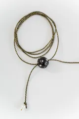 Gargantilla tipo bolo tie de tiento trenzado verde con dije esférico celeste con brillos incrustados.