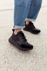 Championes deportivos de cuero en tonos marrón, tostado y marrón oscuro, con detalles de estampado animal print de leopardo en el lateral, suela gruesa blanca y cordones elásticos.