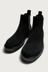 Bota chelsea de cuero con acabado de serraje color negro, con elásticos laterales y tira trasera para facilitar el calce.