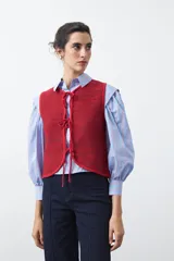Chaleco de punto con efecto jaspeado en color azul, con diseño sin mangas, escote redondeado y cierre frontal mediante lazos ajustables.