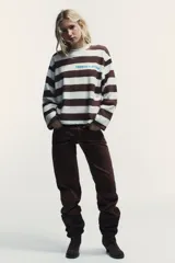 Camiseta de manga larga con cuello redondo y estampado de rayas horizontales en blanco y marrón. Incluye texto azul "TRIBECA MIDTOWN" estampado en el pecho.