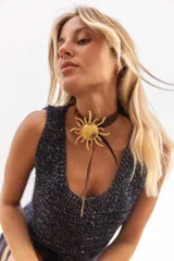 Collar tipo choker con tira de cuero marrón y dije central de sol grande en bronce, con terminación de tira larga y detalle metálico colgante.