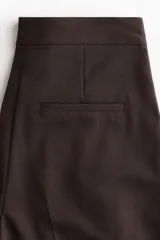 Pantalón palazzo marrón de tiro alto con cierre y corchete oculto, corte holgado con bolsillos en las costuras laterales, bolsillos traseros insertados y piernas amplias con pliegues en la parte delantera.