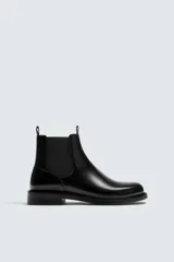 Bota estilo Chelsea de piel negra con elásticos laterales y suela con ligero tacón.