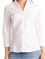 Camisa blanca de algodón con cuello camisero y escote en V. Presenta detalles plisados en el frente, cierre central con botones y mangas tres cuartos con puños abotonados. Los laterales están confeccionados en tejido modal para mayor comodidad.