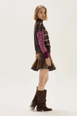 Sweater de cuello tortuga, tejido a rayas horizontales azul marino y blanco. Presenta un bordado de flor roja en el pecho y mangas largas con diseño de rayas en tonos de azul más claro.