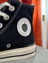 Zapatillas de lona color beige, tipo bota, con cordones marrones, puntera de goma y logo de peach engomado.