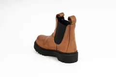 Bota tipo Chelsea de cuero color marrón, con paneles elásticos laterales en color negro, costuras a la vista y suela de goma dentada negra.